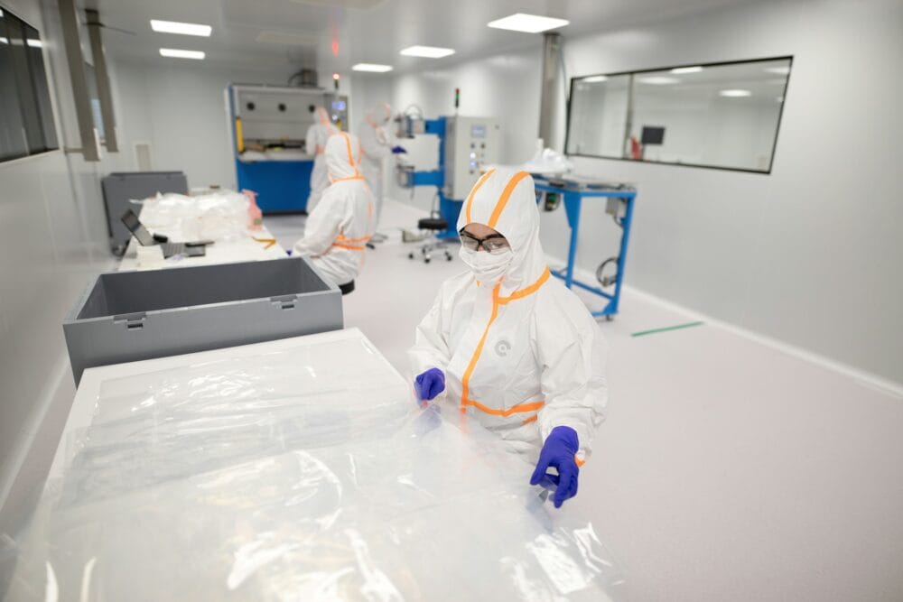Workers in protective suits inside a cleanroom manufacturing facility