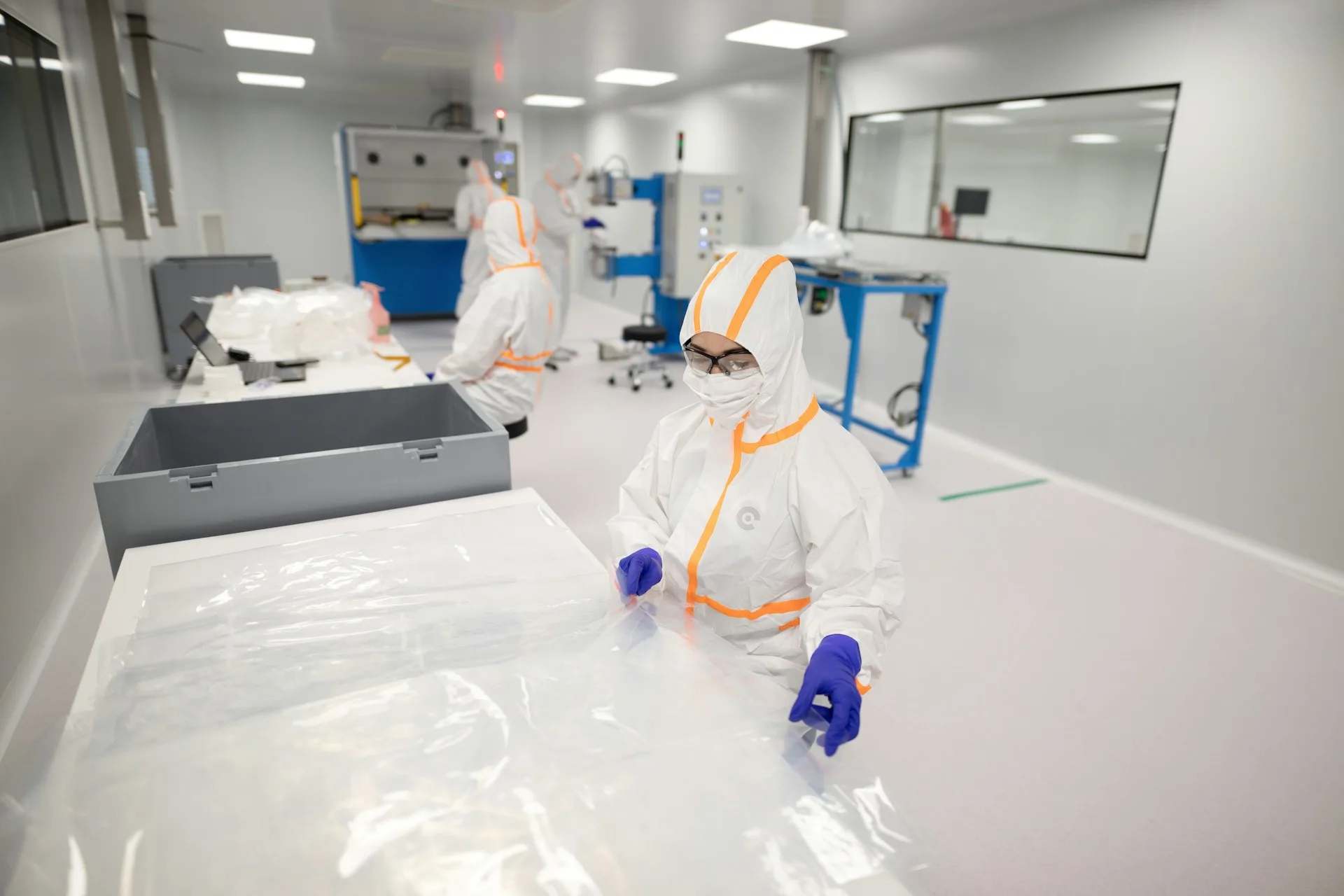 Workers in protective suits inside a cleanroom manufacturing facility